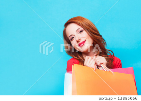 Redhead girl with shopping bags on blue background. Redhead girl with shopping bags on blue background. 13885066