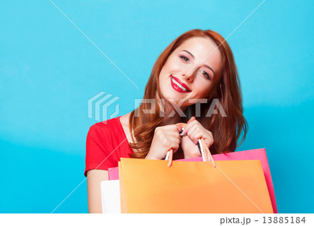 Redhead girl with shopping bags on blue background. 13885184