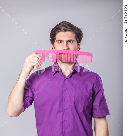 Man with huge comb on gray background. 13885308