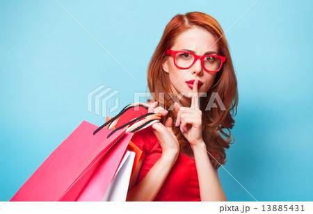 Redhead girl with shopping bags on blue background. 13885431