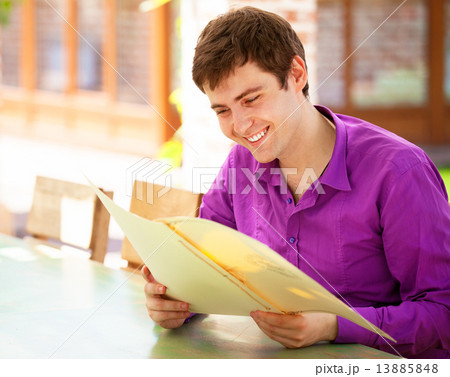 Young man sitting in the cafe and looking in the menu. Young man sitting in the cafe and looking in the menu. 13885848