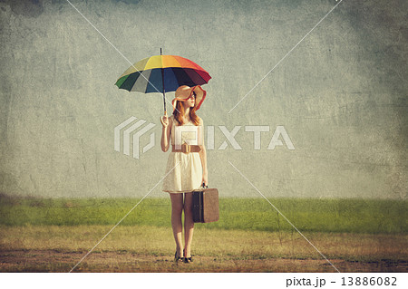 Redhead enchantress with umbrella and suitcase at spring country 13886082