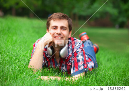 Handsome young man with headphones at green grass Handsome young man with headphones at green grass 13886262