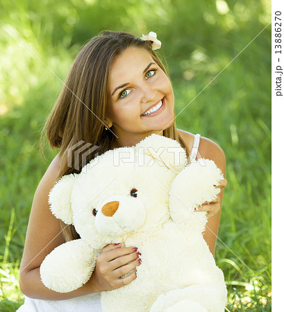 Beautiful teen girl with Teddy bear in the park at green grass. 13886270