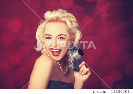 Beautiful blonde women with camera on red background. 13886301