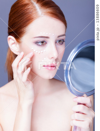 Beauty face of young redhead women with cosmetic cream on a chee 13886609