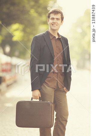 Man with suitcase walking outdoors 13887439