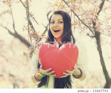 Beautiful girl with toy heart in spring park 13887743