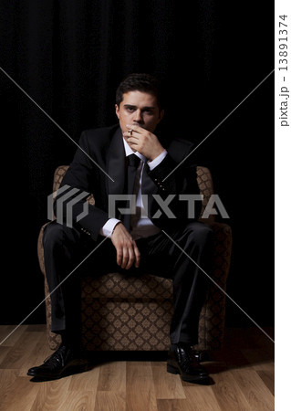 Man with cigarette sitting in vintage armchair Man with cigarette sitting in vintage armchair 13891374