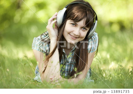 Young fashion girl with headphones at green spring grass. 13891735