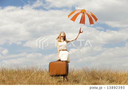 Beautiful redhead girl with umbrella and suitcase at outdoor. 13892393