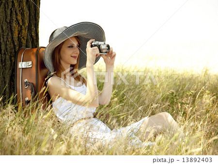 Redhead girl sitting near tree with vintage camera. 13892403