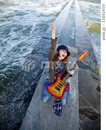 Young red-haired girl play on guitar at windy day. 13892459