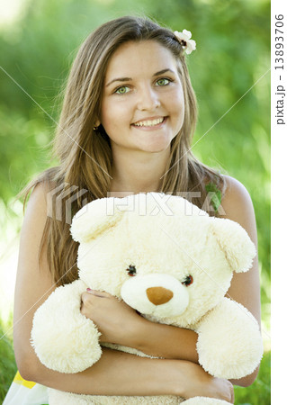 Beautiful teen girl with Teddy bear in the park at green grass. 13893706
