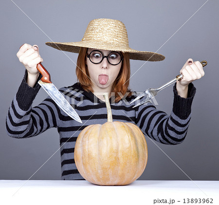 Funny girl in cap and fork with knife try to eat a pumpkin. 13893962