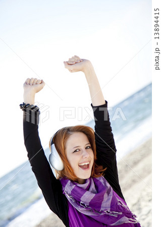 Portrait of red-haired girl with headphone on the beach. 13894415