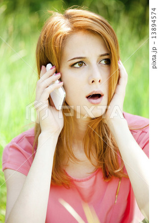 Angry redhead girl with mobile phone at the park. 13894574