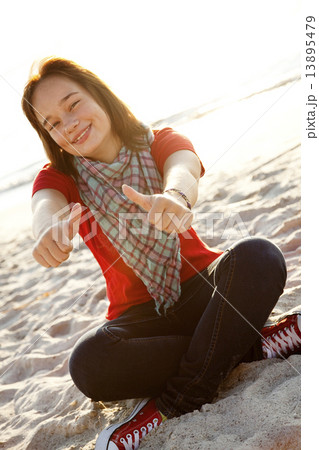 Beautiful brunet girl sitting at sand and show OK 13895479