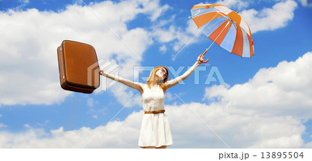 Beautiful redhead girl with umbrella and suitcase at blue sky ba 13895504