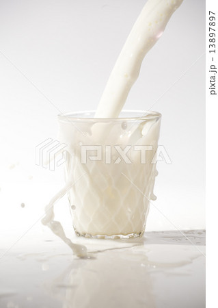 pouring milk in a glass isolated against white background 13897897