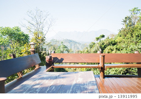 Outdoor wooden seating area with green forest scenery 13911995