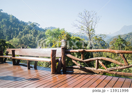 Outdoor wooden seating area with green forest scenery 13911996