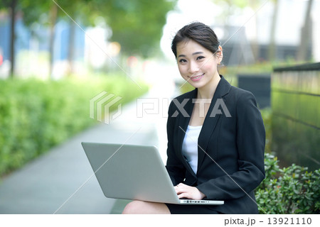 One young successful Chinese businesswoman using laptop sitting along promenade 13921110