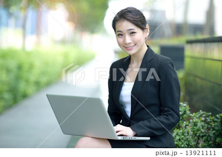 One young successful Chinese businesswoman using laptop sitting along promenade 13921111