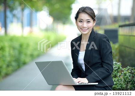 One young successful Chinese businesswoman using laptop sitting along promenade 13921112