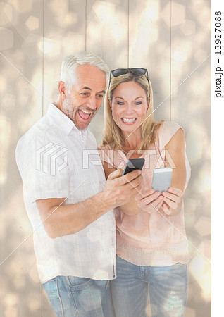 Composite image of happy couple looking at their smartphones 13927088