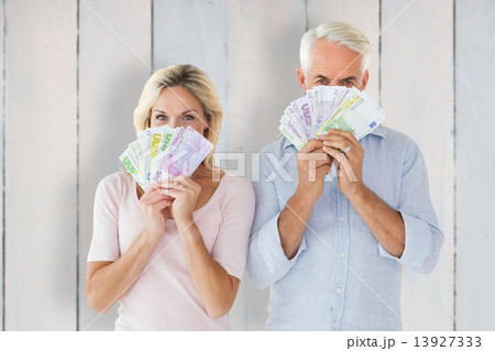 Composite image of happy couple flashing their cash 13927333