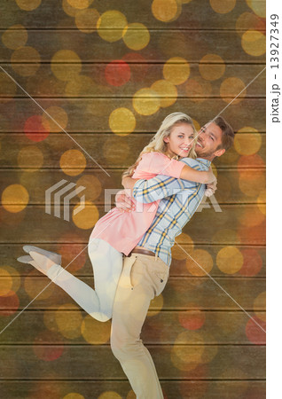 Composite image of handsome man picking up and hugging his girlf 13927349