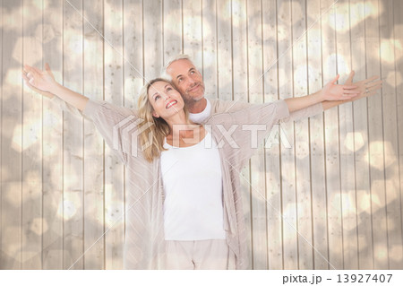 Composite image of happy couple standing with arms outstretched Composite image of happy couple standing with arms outstretched 13927407