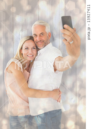 Composite image of happy couple posing for a selfie 13927411