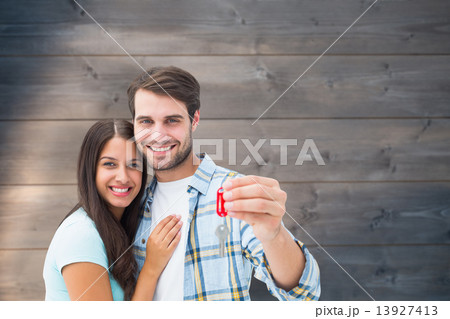 Composite image of happy young couple holding new house key Composite image of happy young couple holding new house key 13927413