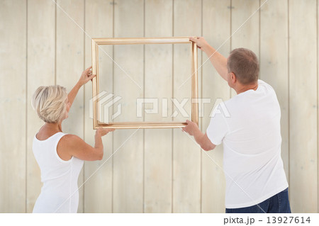 Composite image of mature couple hanging up picture frame Composite image of mature couple hanging up picture frame 13927614