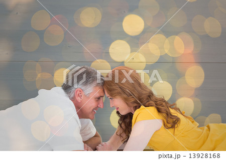 Composite image of casual couple lying on floor with piggy bank 13928168