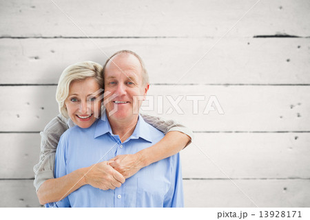 Composite image of happy mature couple embracing smiling at came 13928171
