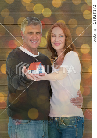 Composite image of casual couple holding small house 13928172