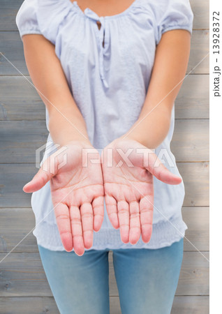 Composite image of casual young woman holding hands out 13928372