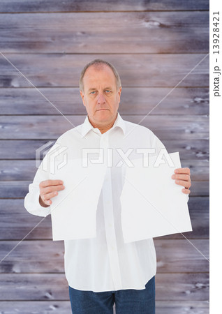 Composite image of serious man holding torn sheet of paper 13928421
