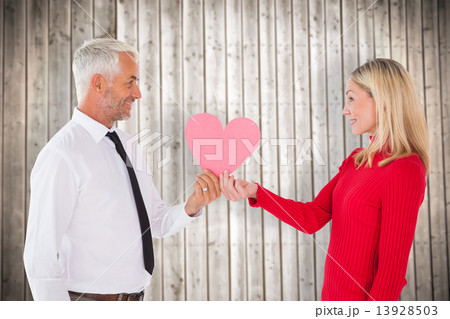 Composite image of handsome man getting a heart card form wife Composite image of handsome man getting a heart card form wife 13928503
