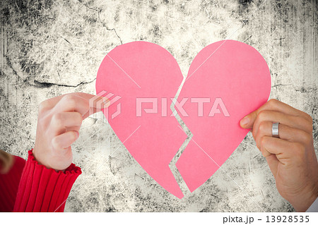 Composite image of couple holding two halves of broken heart 13928535