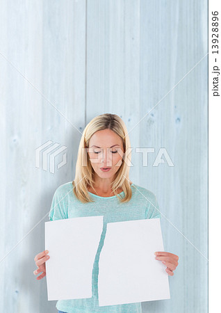 Composite image of serious woman holding torn sheet of paper 13928896