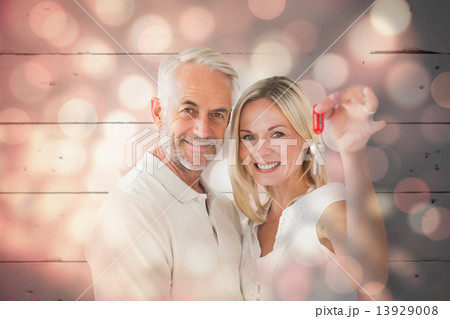 Composite image of happy couple showing their new house key Composite image of happy couple showing their new house key 13929008