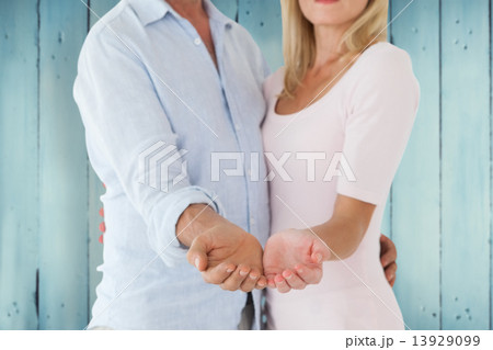 Composite image of happy couple holding their hands out Composite image of happy couple holding their hands out 13929099