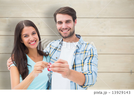 Composite image of happy young couple showing new house key Composite image of happy young couple showing new house key 13929143