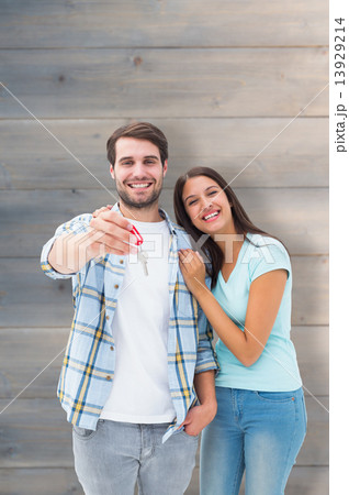 Composite image of happy young couple showing new house key Composite image of happy young couple showing new house key 13929214