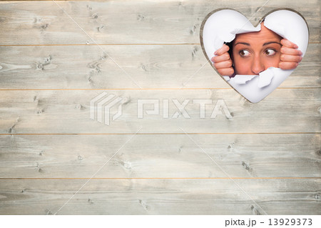 Composite image of young woman looking through paper rip 13929373