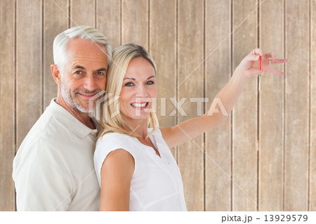 Composite image of happy couple showing their new house key 13929579